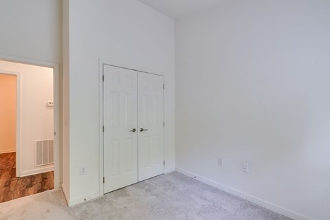 a bedroom with white walls and a door to a closet