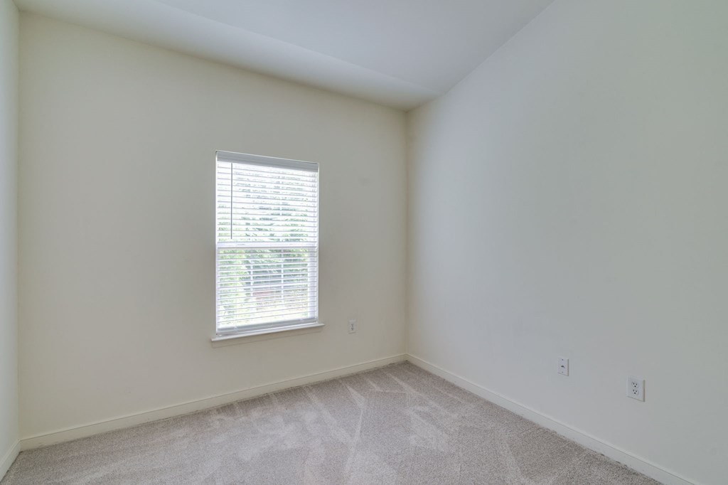 an empty room with a window and white walls