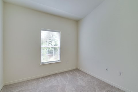 an empty room with a window and white walls