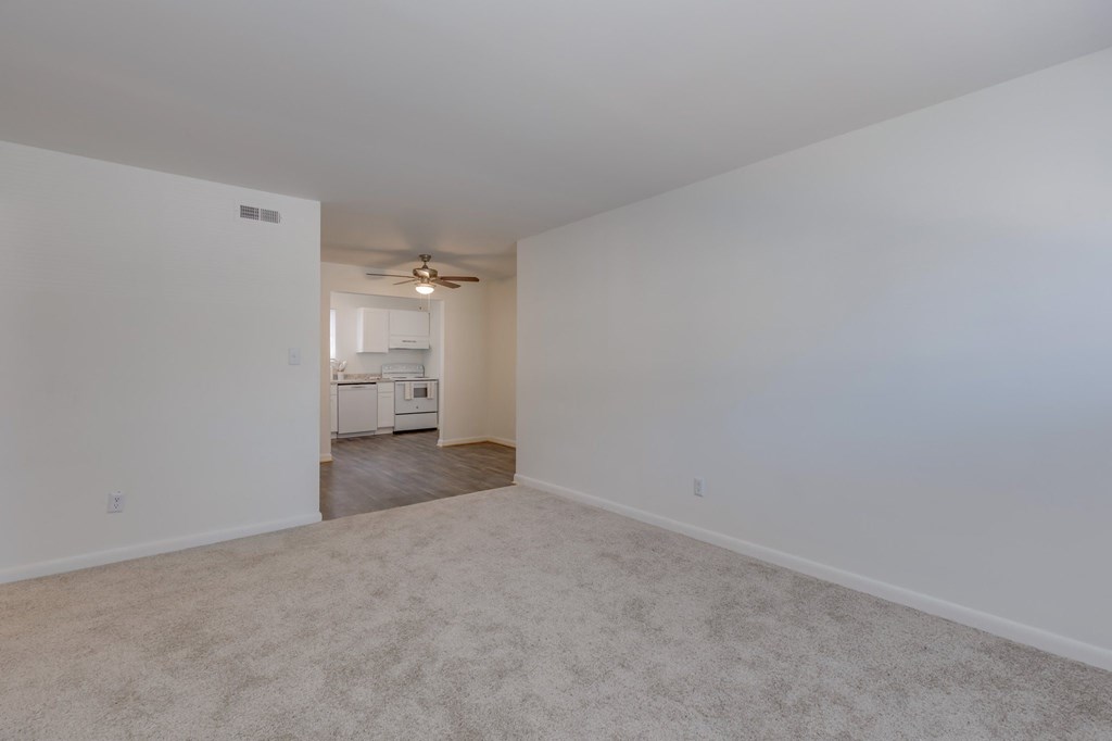 an empty living room with white walls and a ceiling fan