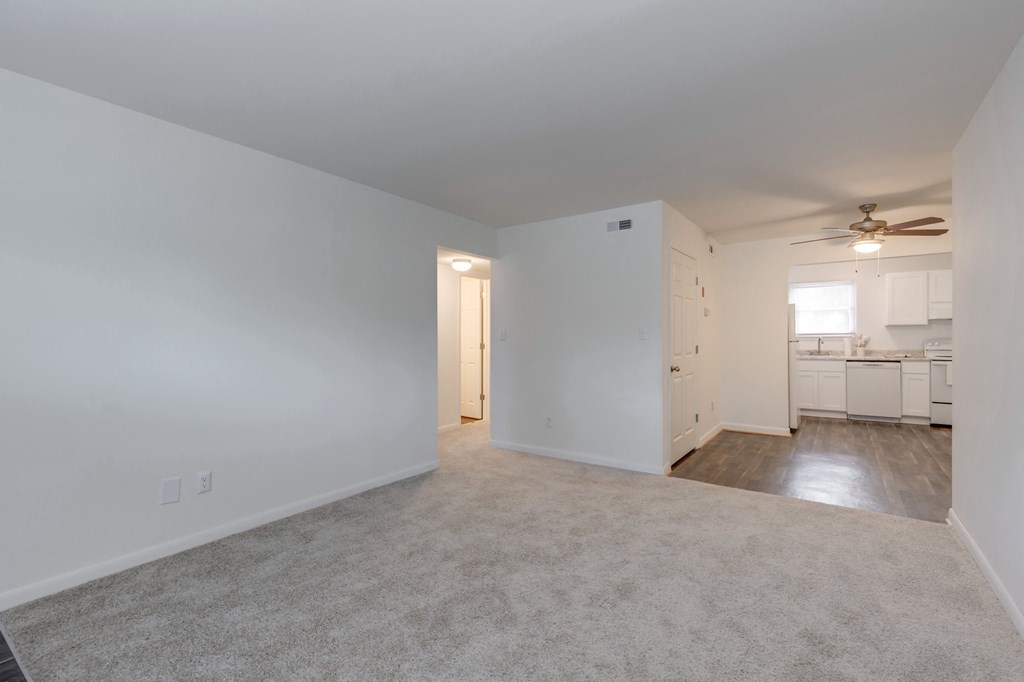 an empty living room with white walls and a ceiling fan