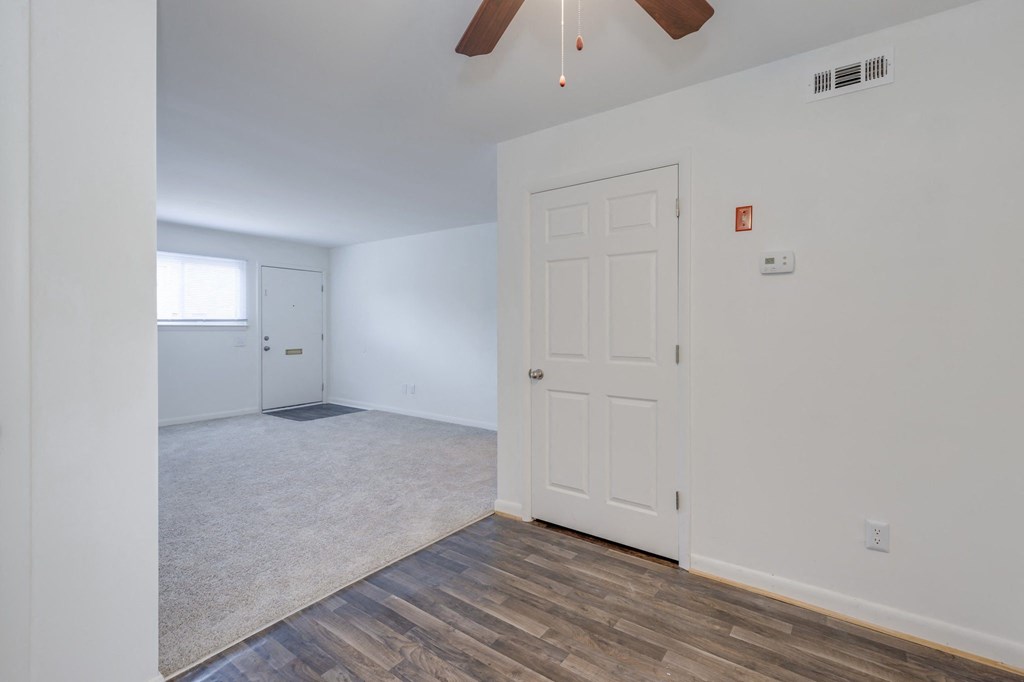 the living room and dining room of an empty house with a white door