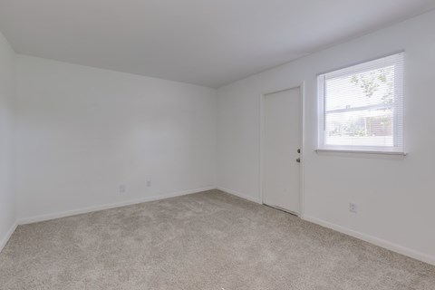 a bedroom with white walls and carpet and a window
