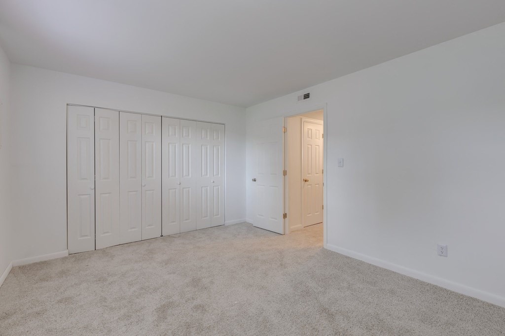 a bedroom with white walls and white closets and white doors