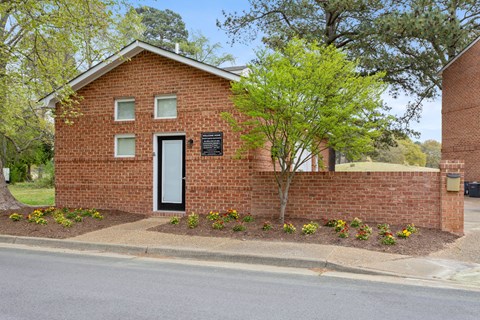 the front of a brick building with a door and a tree