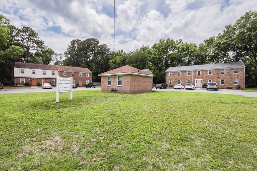 a small brick building sitting in the middle of a grass field
