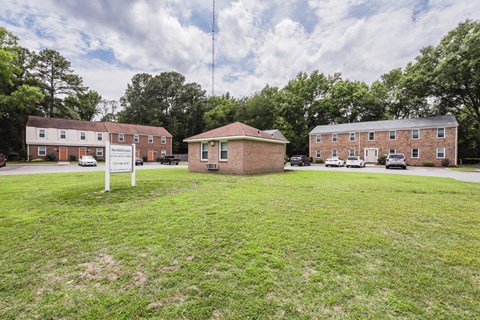 a small brick building sitting in the middle of a grass field