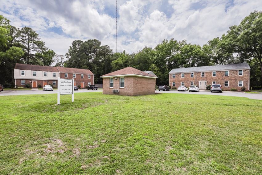 a small brick building sitting in the middle of a grass field