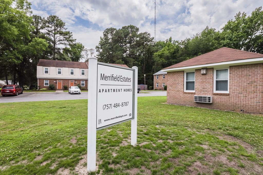 a sign in a yard in front of a brick house