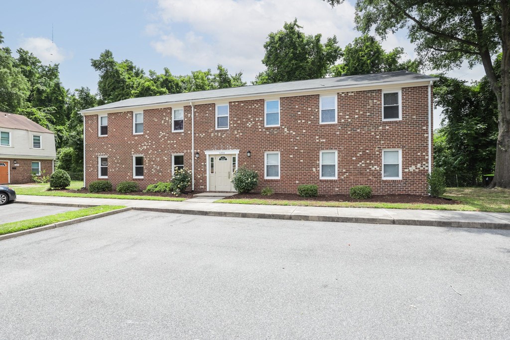 a brick house with a white door and a street in front of it