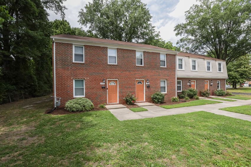 a brick apartment building with a sidewalk and grass