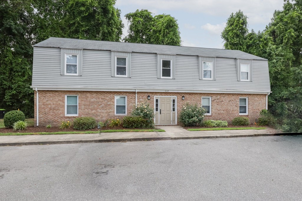 the front of a brick house with a gray roof