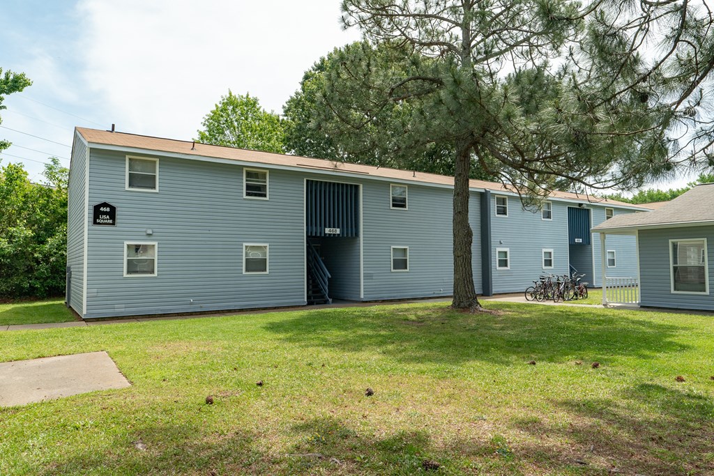 the exterior of a blue house with a yard and a tree
