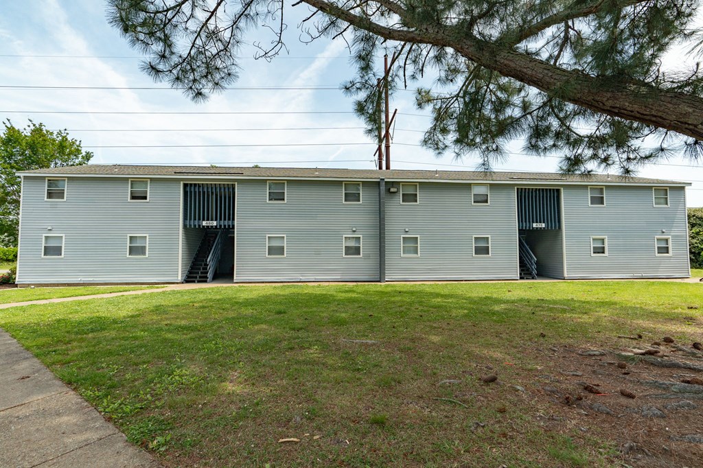 a gray building with two garage doors and a lawn