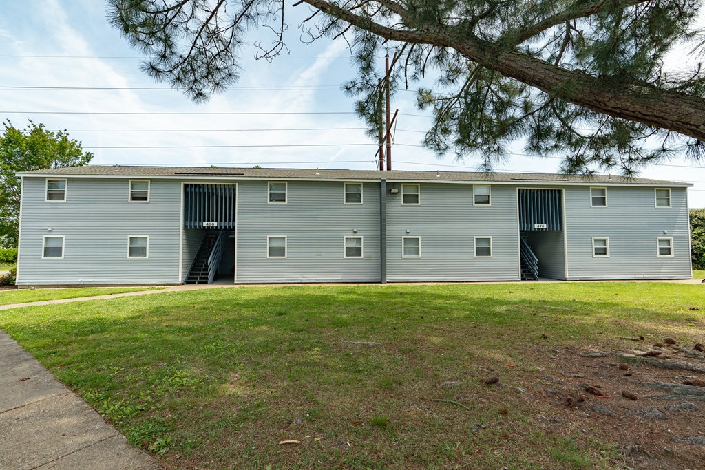a gray building with two garage doors and a lawn
