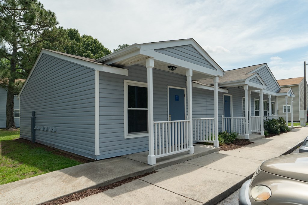 a blue house with a porch and a sidewalk in front of it
