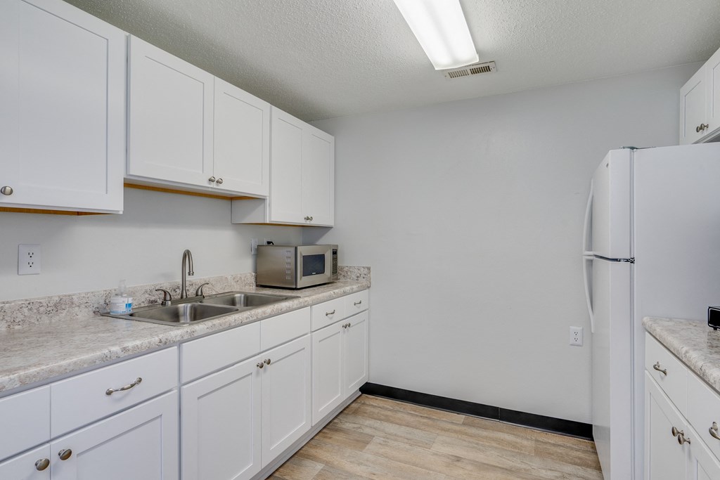 a kitchen with white cabinets and a sink and a refrigerator