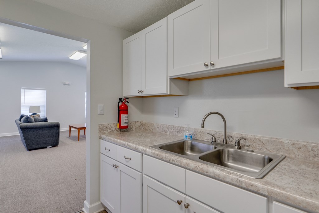 a kitchen with a sink and cabinets and a living room with a couch