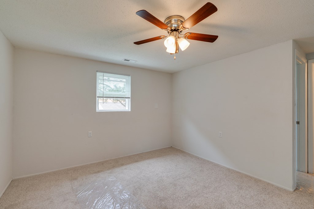 an empty room with a ceiling fan and a window