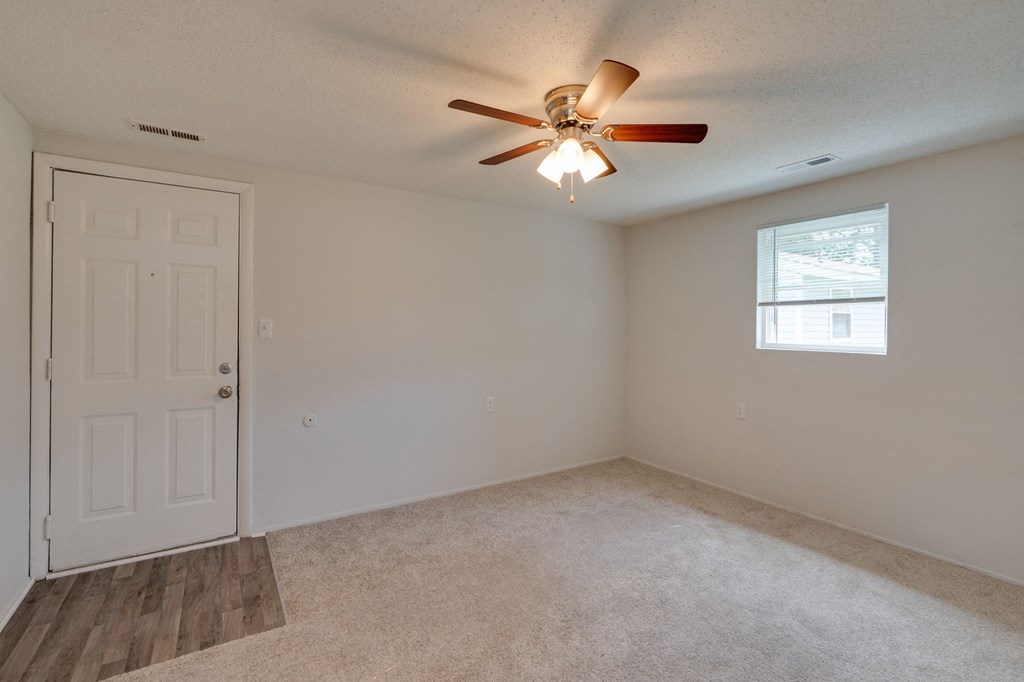 an empty bedroom with a ceiling fan and a door