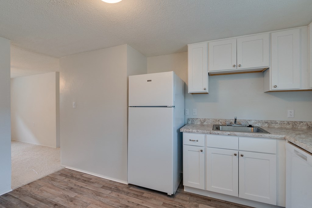 an empty kitchen with white cabinets and a refrigerator