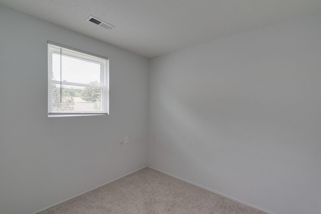 an empty room with a window and white walls