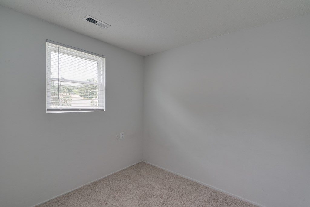 an empty room with a window and white walls