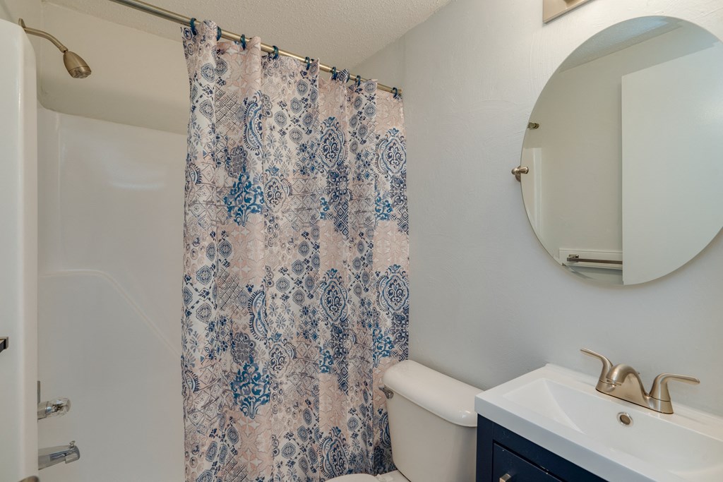 a bathroom with a shower curtain and a sink and a toilet