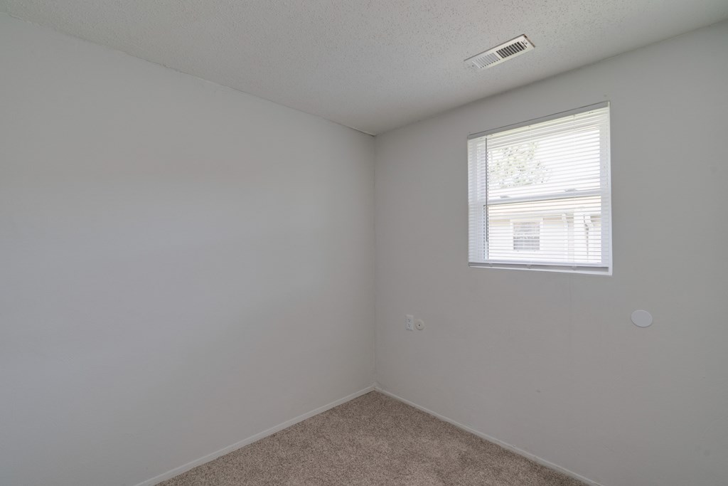 a bedroom with white walls and a window