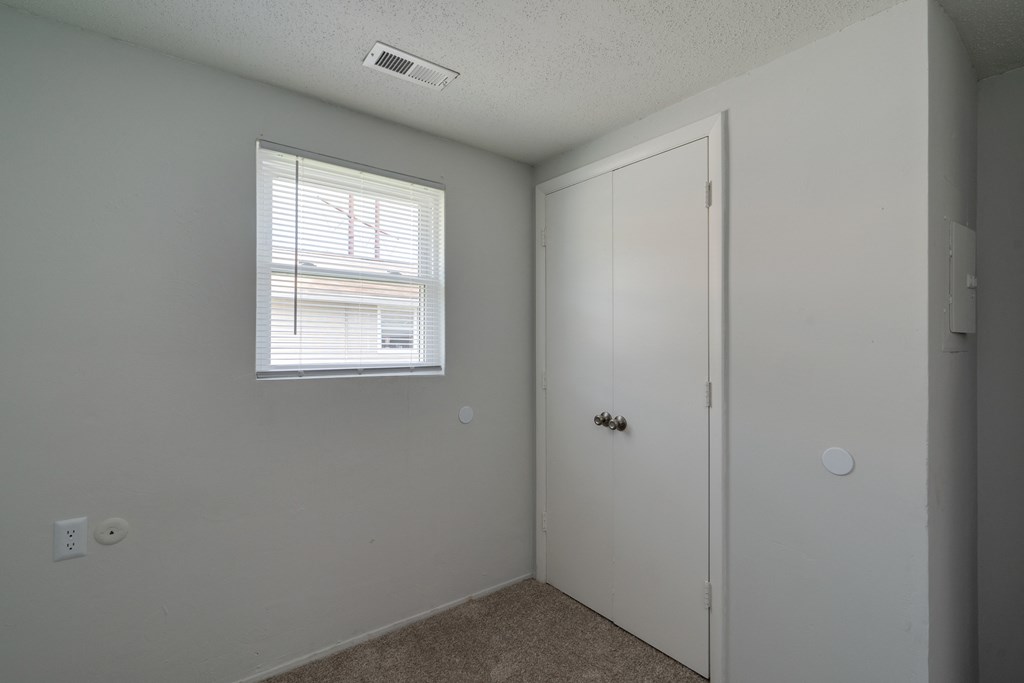 an empty bedroom with a door and a window