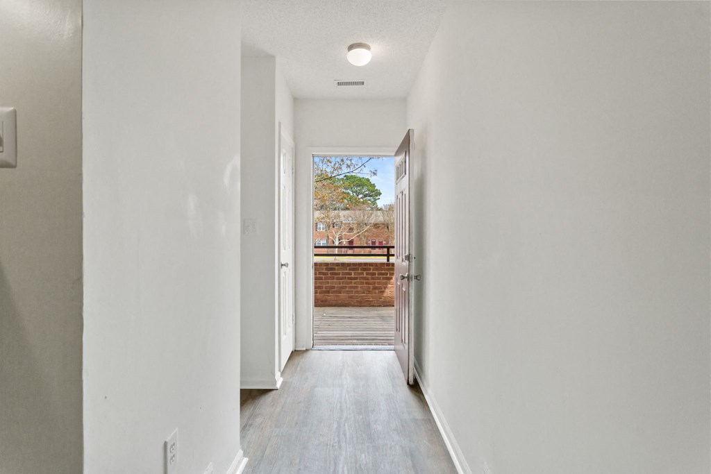 a hallway with white walls and a door to a balcony