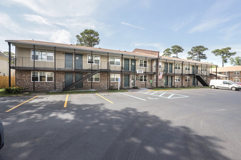 an exterior view of an apartment building with a parking lot