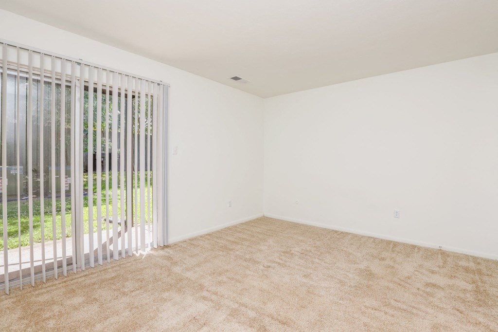 an empty living room with white walls and a sliding glass door