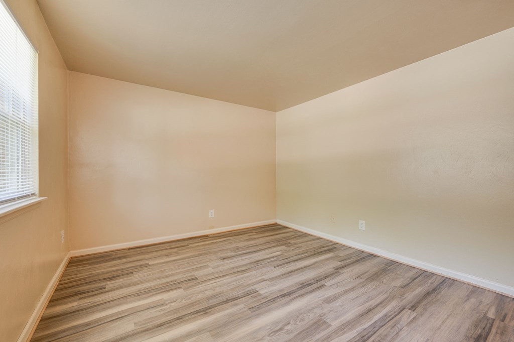 an empty room with wood flooring and a window