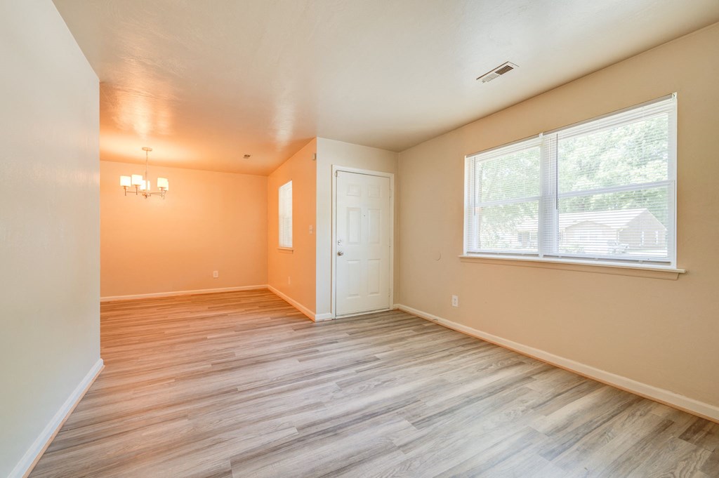 an empty living room with wood floors and a large window