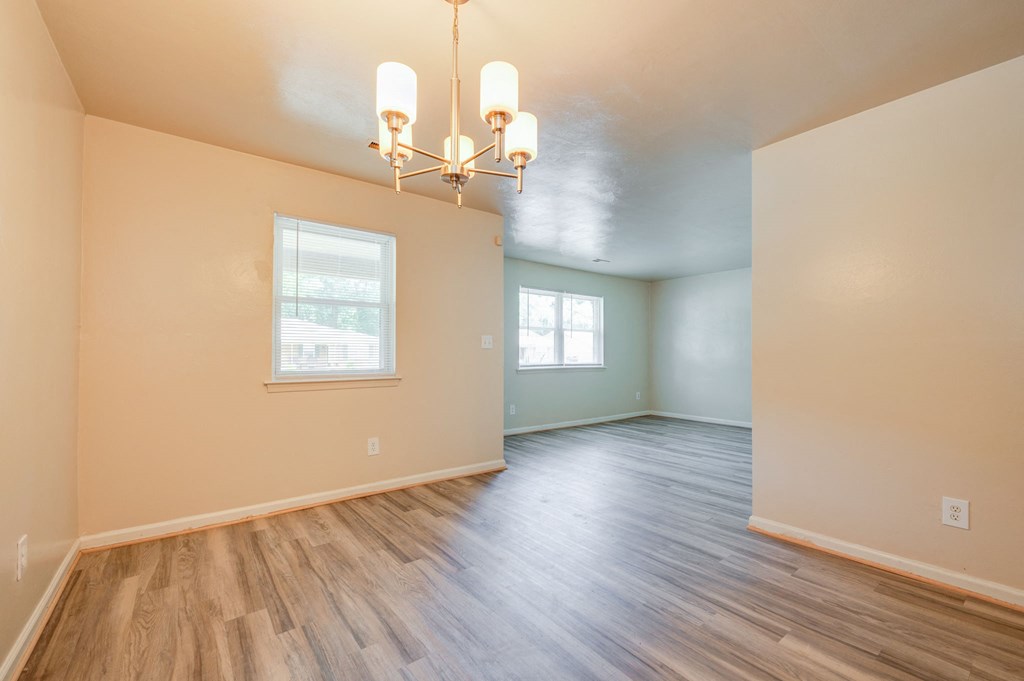 an empty living room with hard wood floors and a chandelier