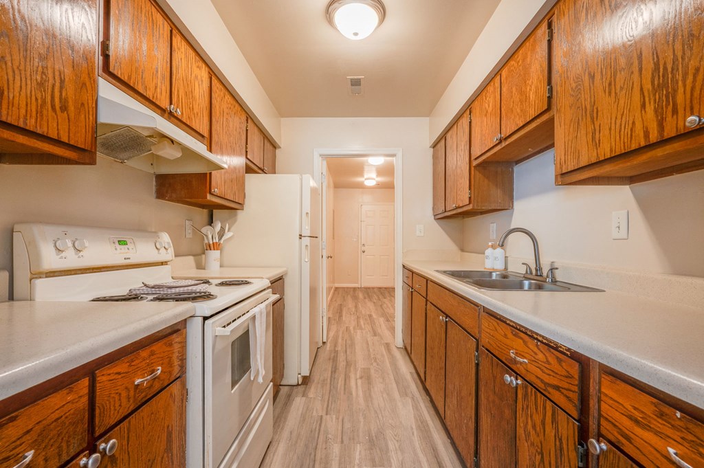 a kitchen with wood cabinets and white appliances and a sink