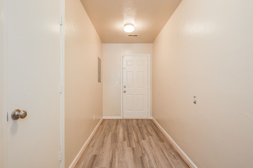 an empty room with a white door and wood flooring