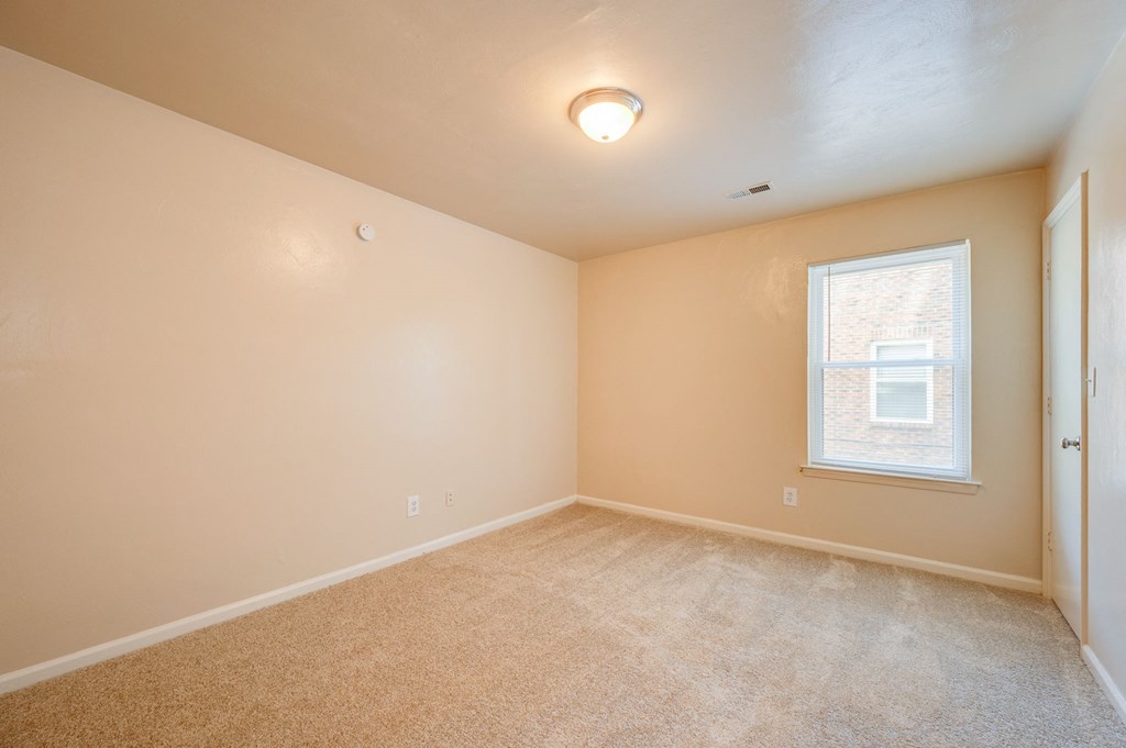 an empty living room with carpet and a window
