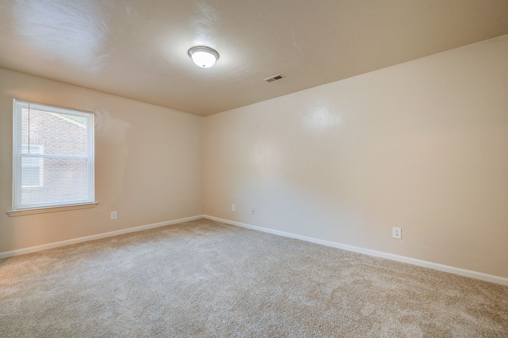 an empty living room with carpet and a window