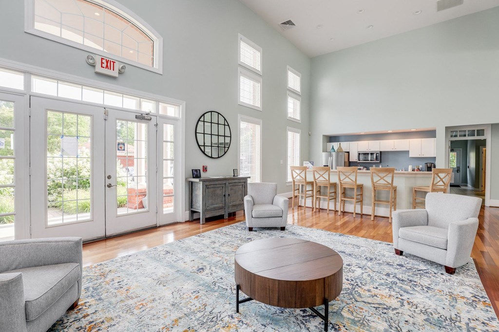 a living room with two chairs and a coffee table and a kitchen in the background