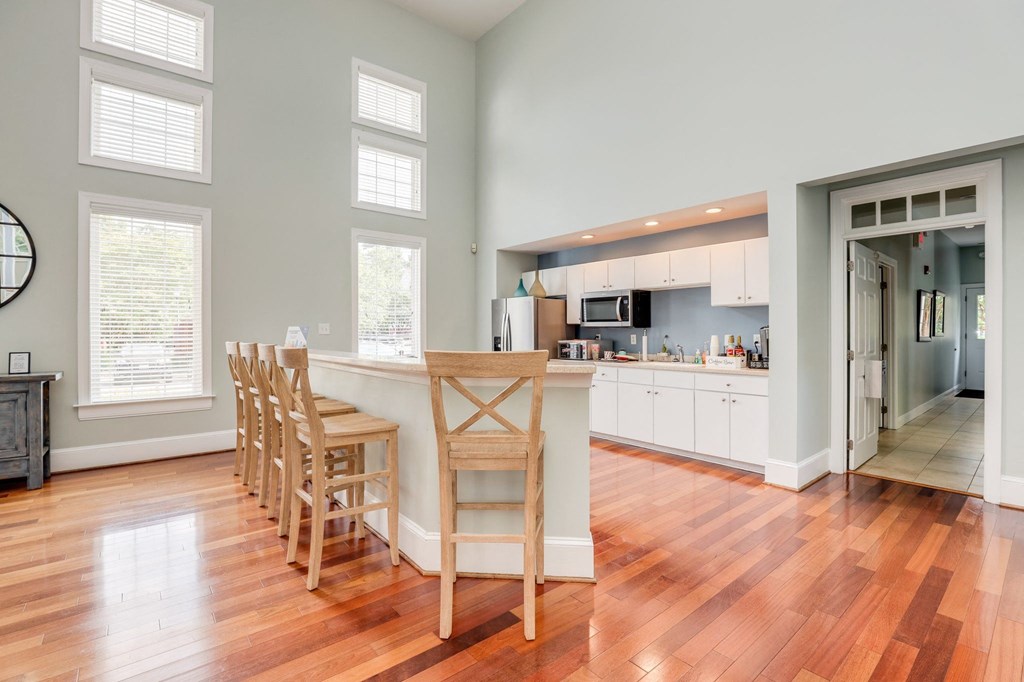 a living room with a kitchen and a bar with wooden chairs