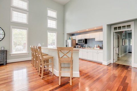 a living room with a kitchen and a bar with wooden chairs