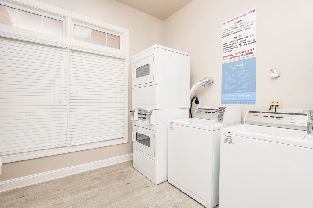a laundry room with two washer and dryers and a window with white appliances