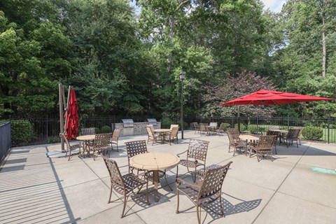 a patio with tables and chairs and a red umbrella