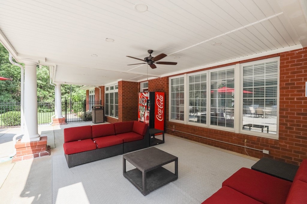 a porch with red couches and a coke machine on the wall