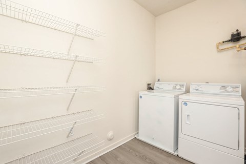 a white room with two washes and a dryer in it and a shelf