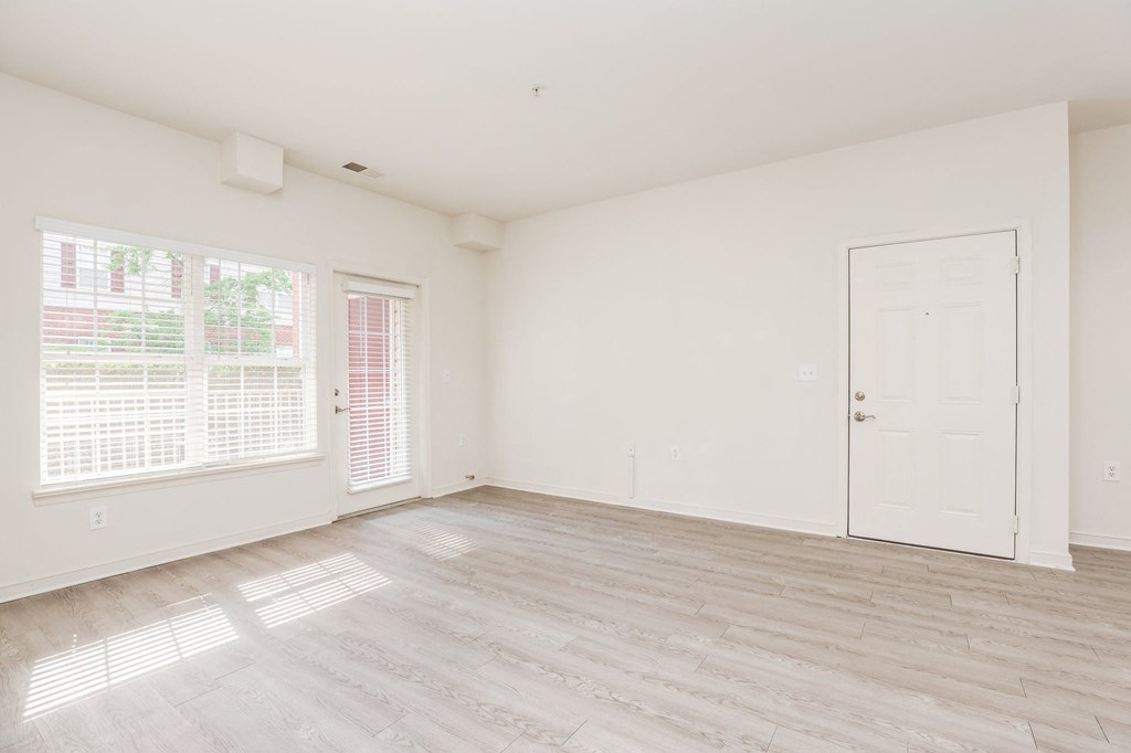 an empty living room with a white door and window