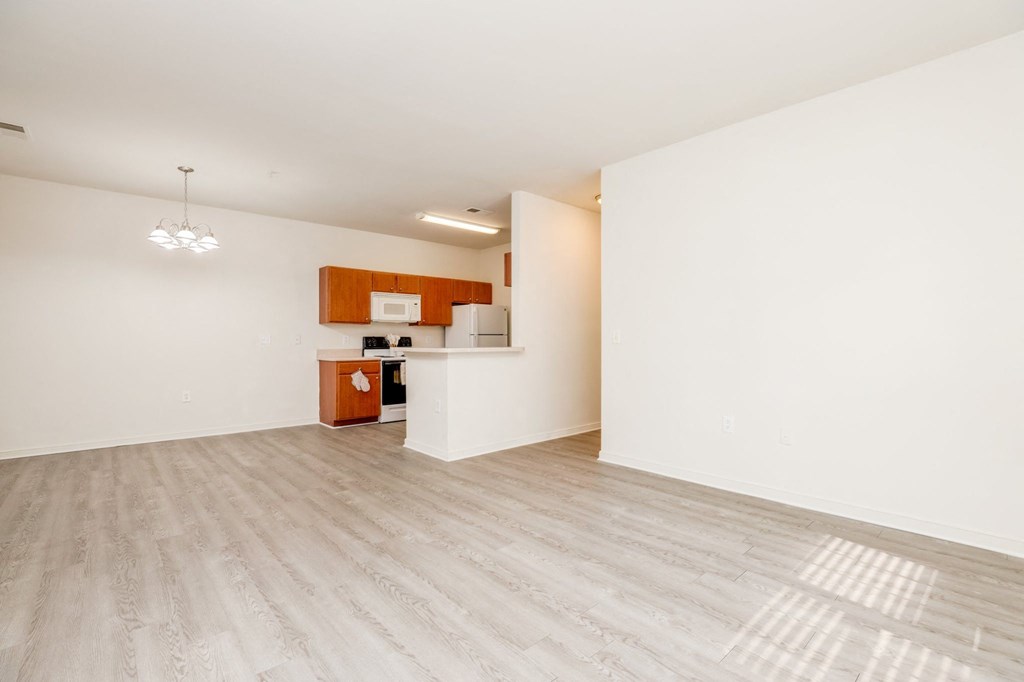 a living room and kitchen with white walls and wood floors