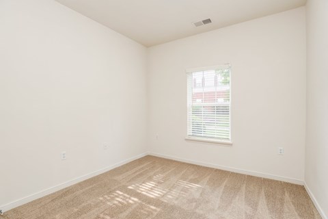 a bedroom with white walls and carpet and a window